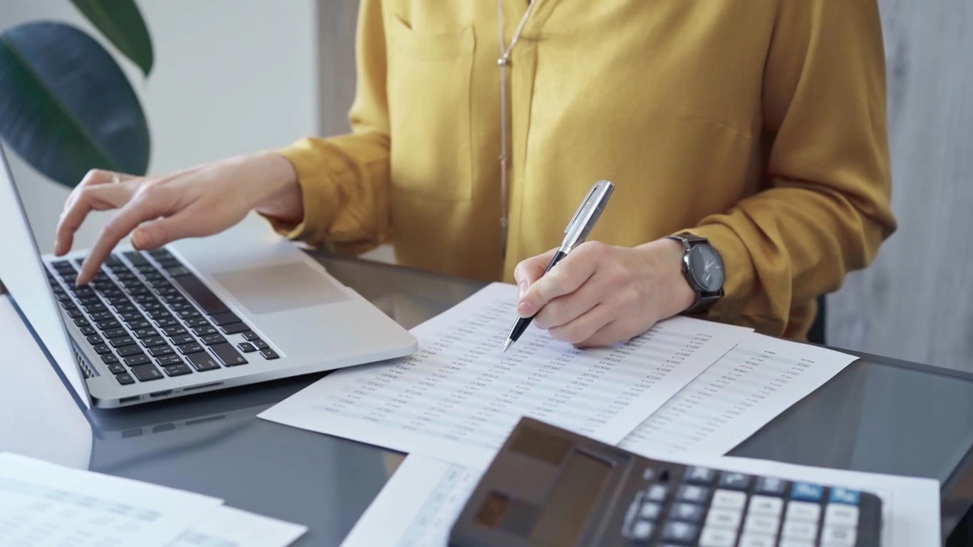 A tax and accounting professional working on her laptop and printed spreadsheets